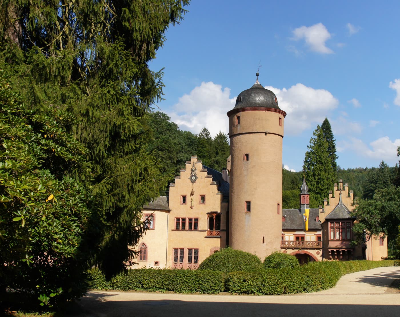 Das Wasserschloss Mespelbrunn mit rundem Turm hinter Bäumen